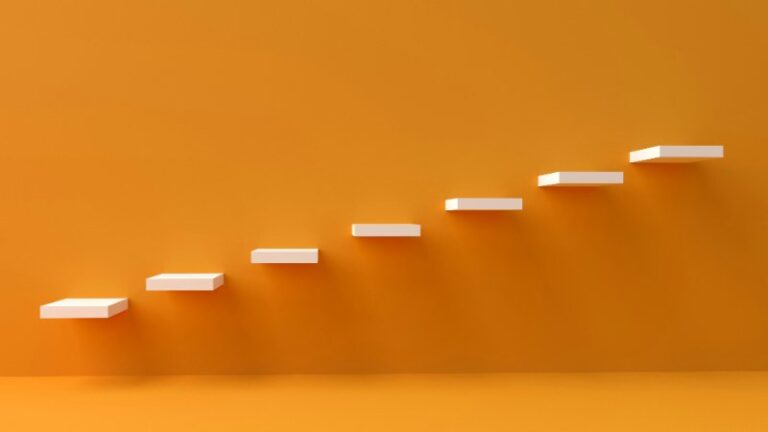 Minimalist image of ascending white steps against an orange background, symbolizing progress and nervous system regulation in therapy.