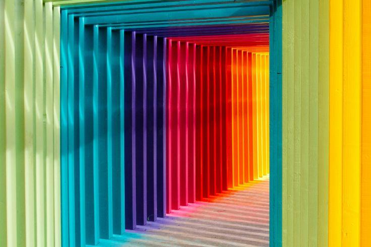 A vibrant tunnel of rainbow-colored slats symbolizing a journey of personal growth. The gradient of colors represents diverse values and evolving goals, guiding individuals from uncertainty to clarity and purpose.