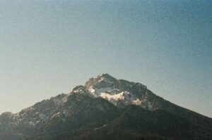 A rugged mountain peak with patches of snow under a clear blue sky, symbolizing resilience and inner strength.