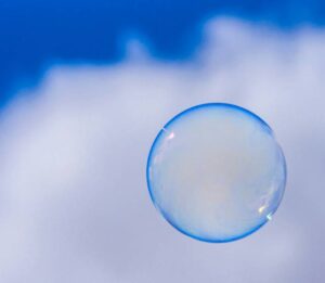 A single soap bubble floating against a blue sky and white clouds, symbolizing clarity and perspective in cognitive behavioral therapy.
