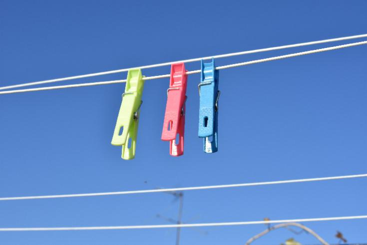 Three colorful clothespins on a laundry line against blue sky—symbolizing shared household tasks, fairness, and teamwork in relationships.