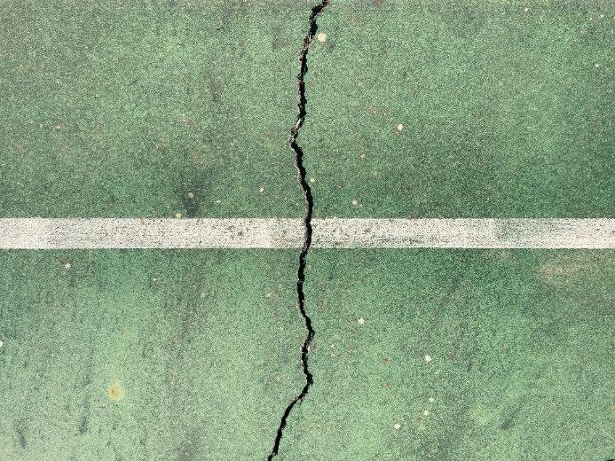 Cracked green surface with a white line symbolizing stress and imbalance, representing the need for stress management strategies.