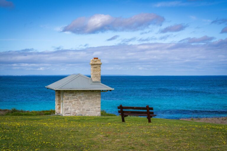Quiet coastal scene with a single bench overlooking the ocean, reflecting space, calm, and comfort in solitude.