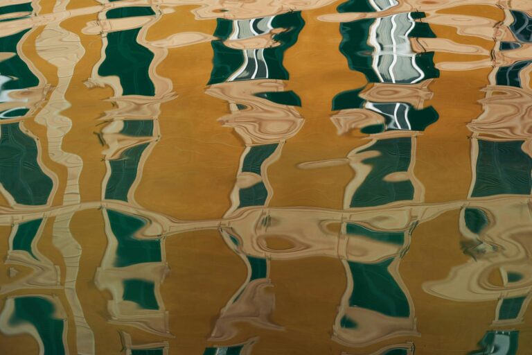 Distorted reflections of structured shapes on a surface, creating fluid, wavy patterns that soften and blur the original form